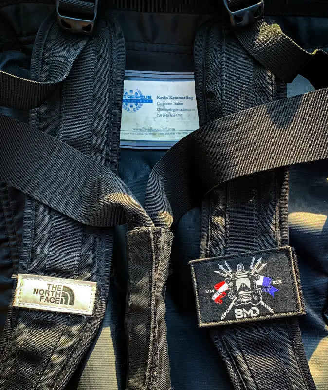 Black backpack with patches and Solas tape slap strap, perfect for first responders