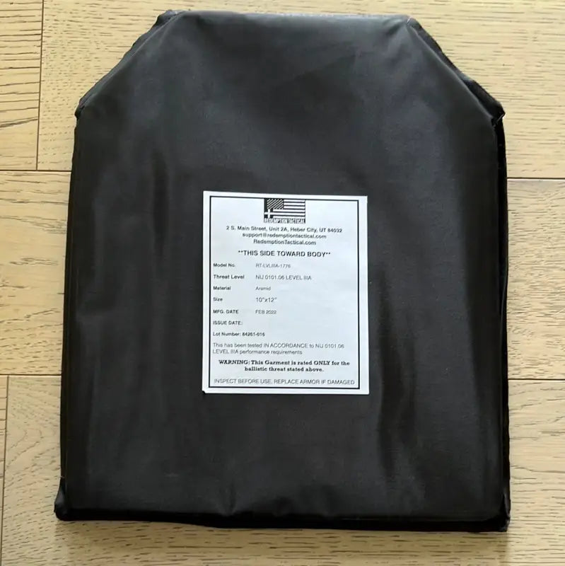 Black ballistic plate with white label showing model threat level and size for body armor