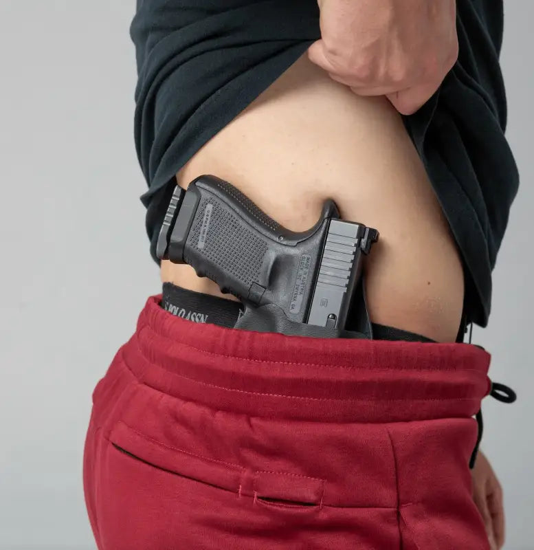 Black handgun tucked into waistband with Carrier Joggers Mk.II for concealed carry and retention belt functionality