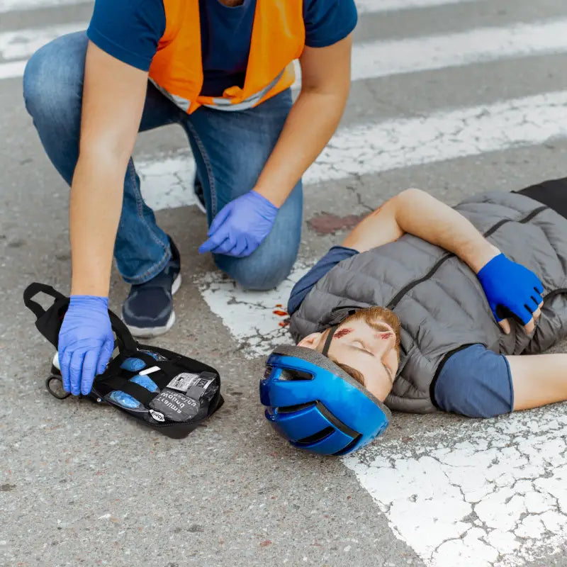 Injured cyclist with first responder using Trauma IFAK Kit, ideal for firefighters and police