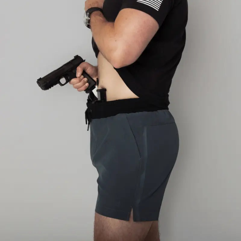 Man holding a handgun wearing Carrier Training Shorts Mk.II for concealed carry training