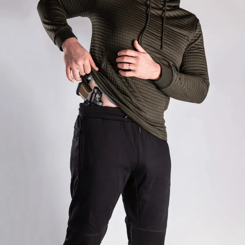 Man concealing handgun with Carrier Joggers Mk.II featuring concealed carry and retention belt