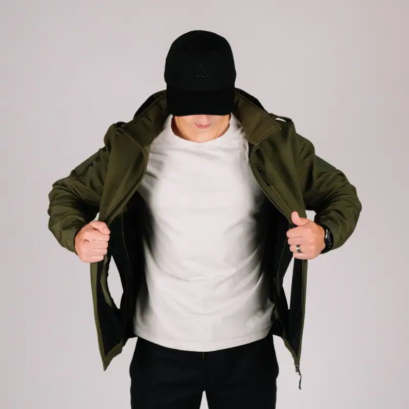 Man in olive tactical jacket Bravo with hand pocket and black cap