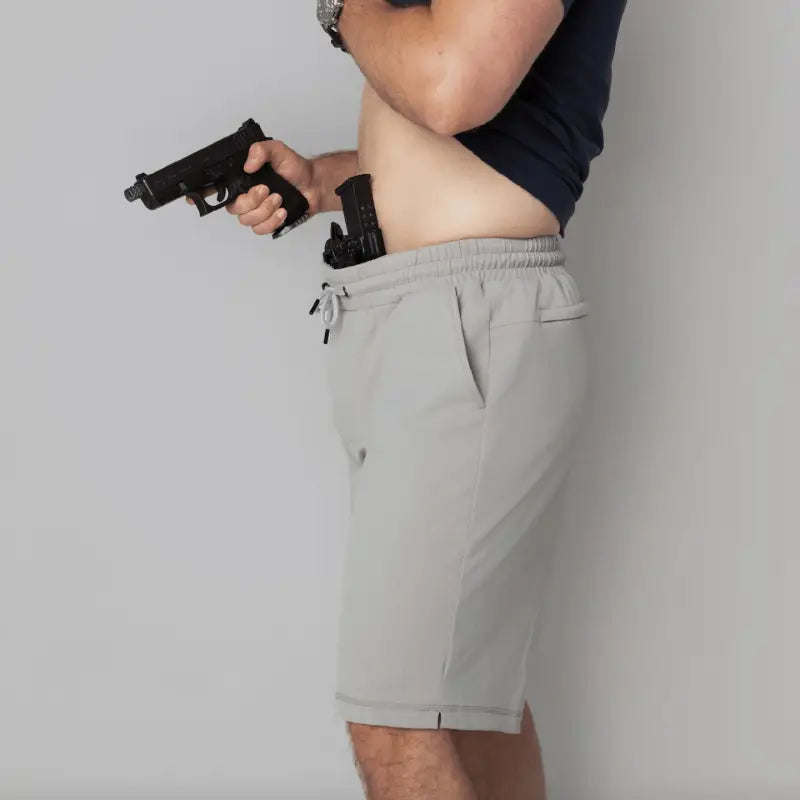 Man holding two handguns wearing Carrier Shorts Mk.II for concealed carry by Arrowhead Tactical Apparel