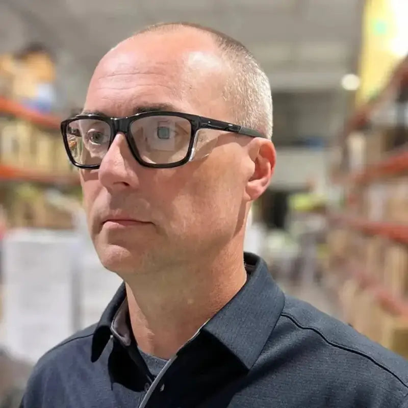 Person wearing black-rimmed glasses showcasing Metel M40 Safety Glasses with polycarbonate lenses
