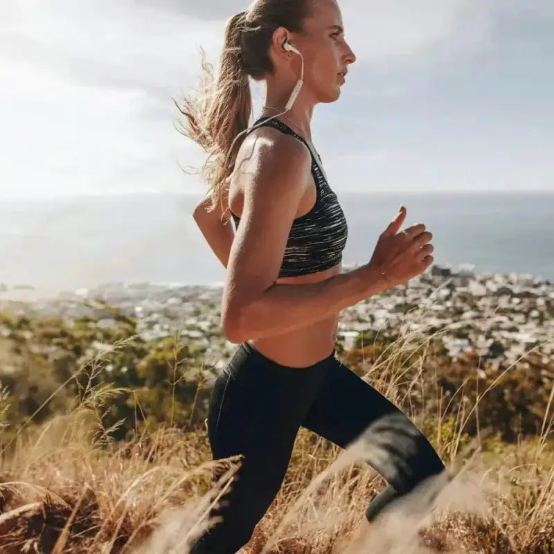 Runner in Womenâs Flex-Fit Compression Capri on a hillside trail for outdoor exercise