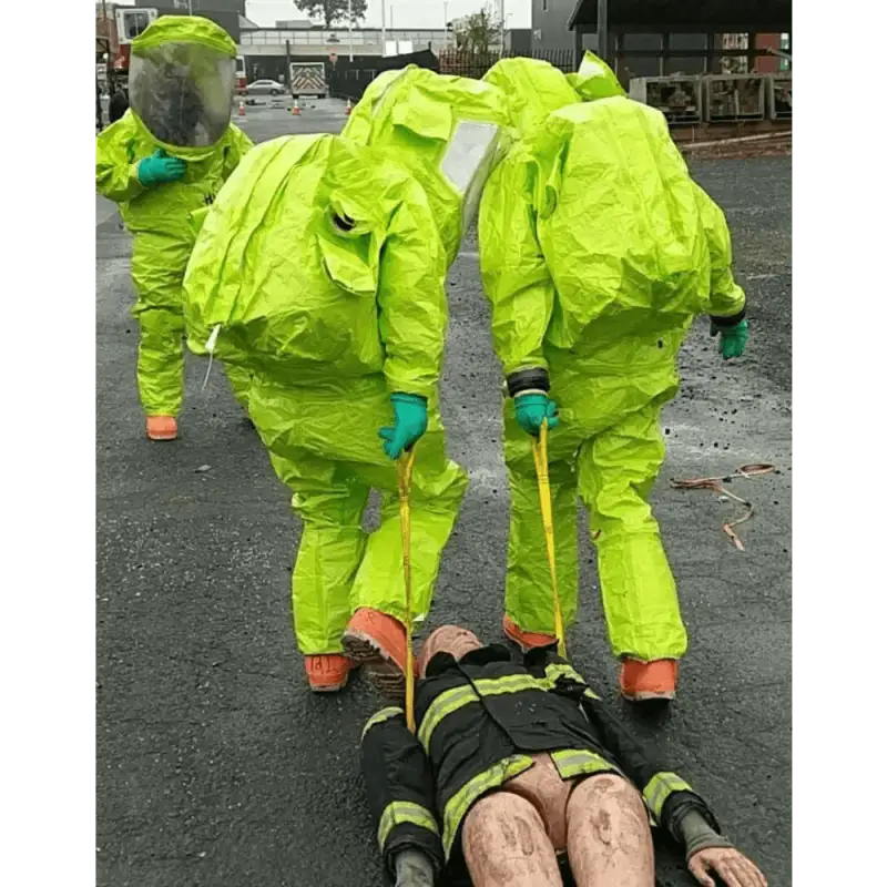 Two hazmat-suited figures using a Multi-Loop Rescue Strap in a critical examination