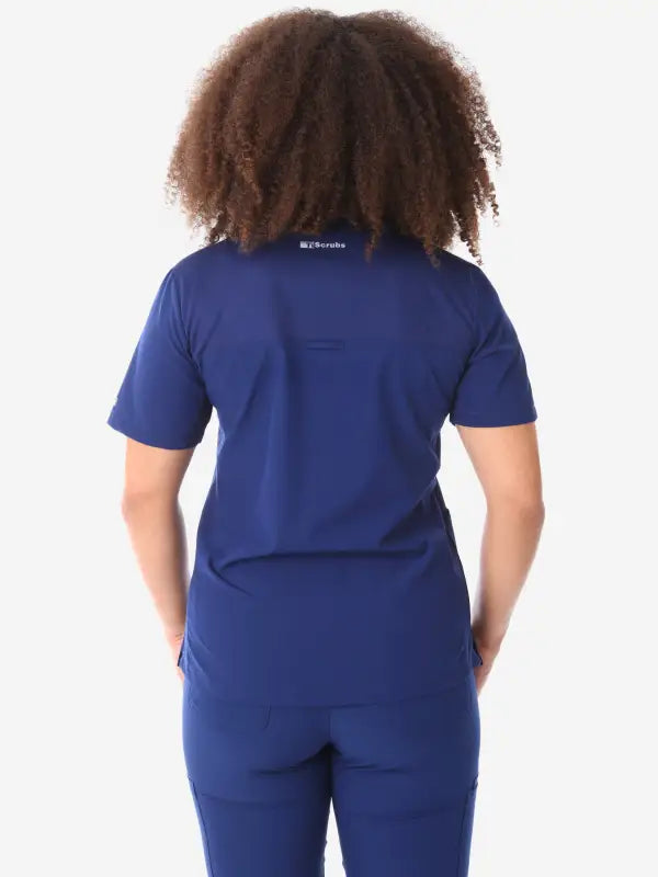 Back view of navy blue women’s four-pocket scrub uniform with visible curly hair