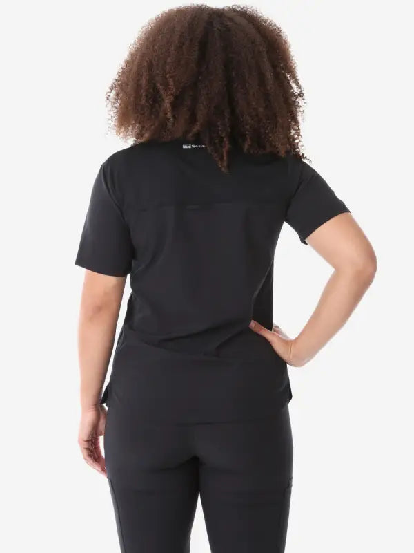 Black women’s four-pocket scrub set with short-sleeved top and fitted pants shown from behind
