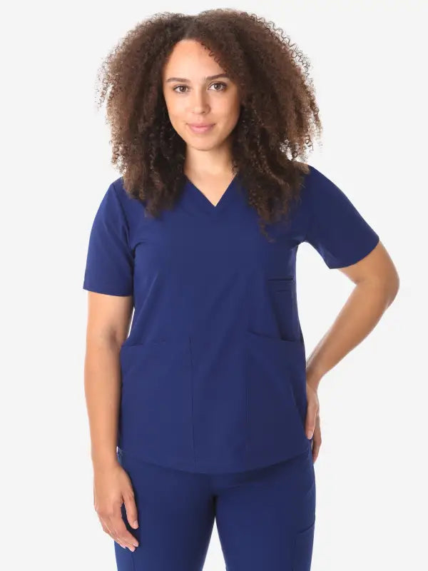 Navy blue women’s four-pocket scrub top with V-neck design for healthcare professionals