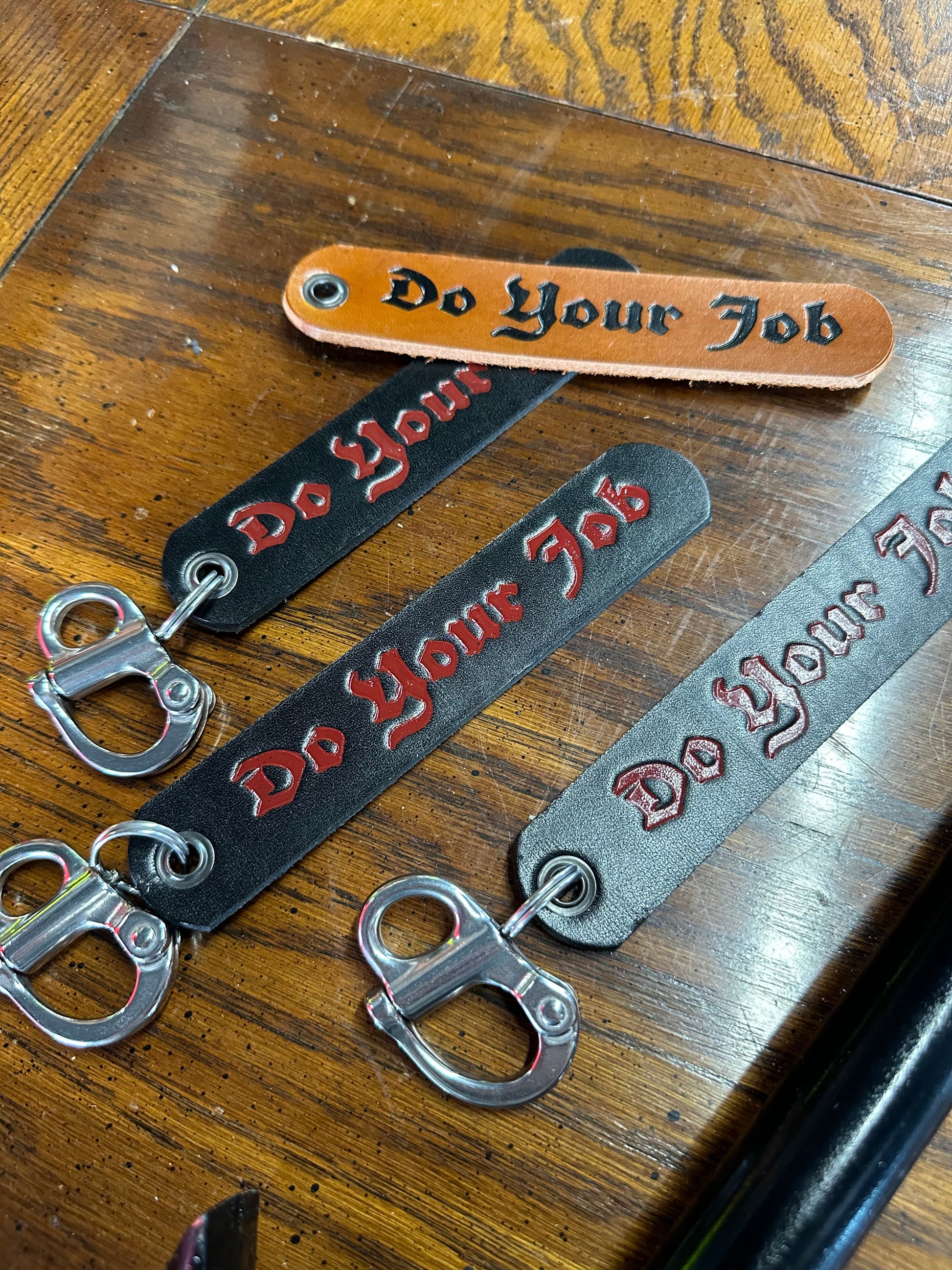 Close-up view of the DO YOUR JOB SCBA quick release clip demonstrating its premium construction and genuine leather strap for firefighters.