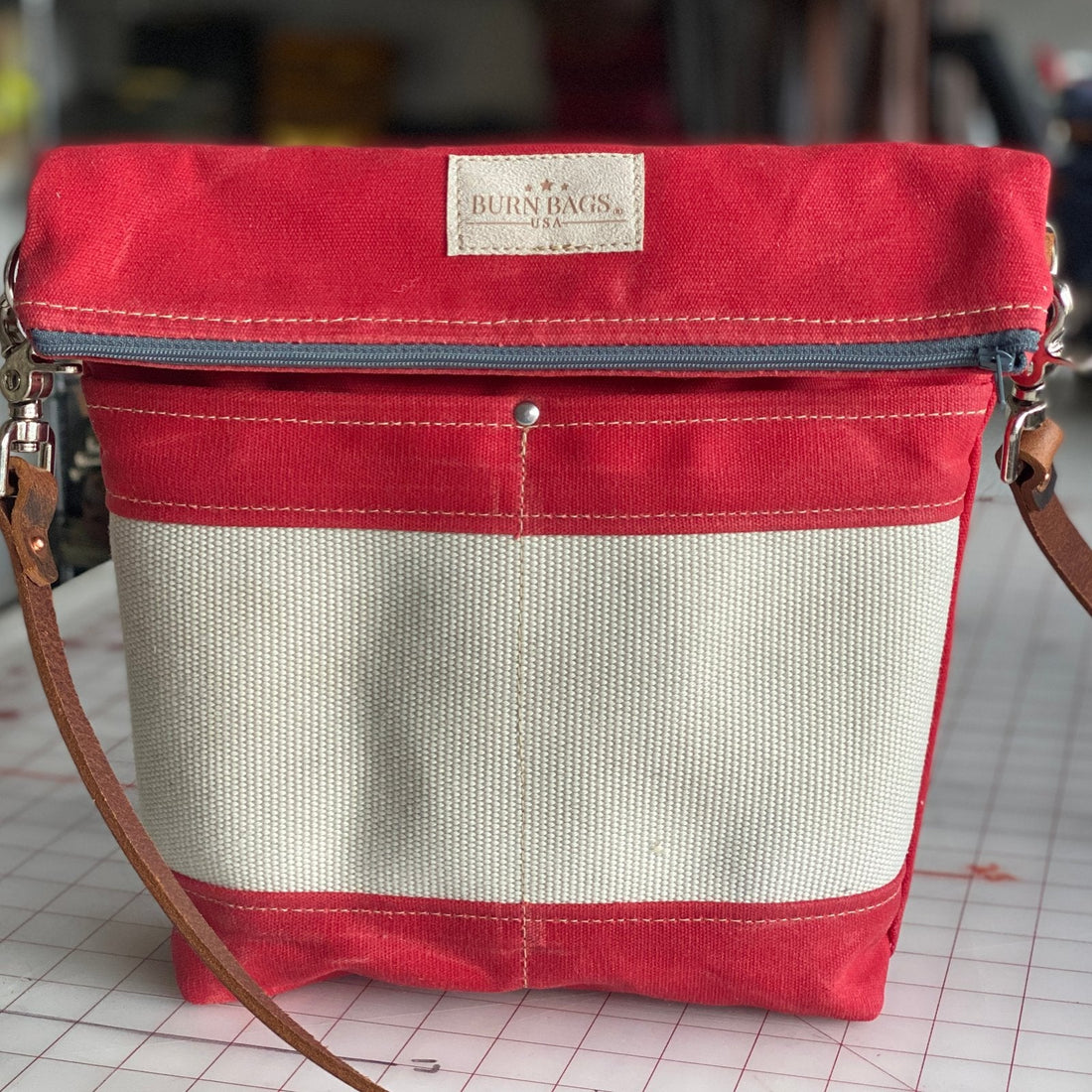 Crossbody Burn Bag in Engine Red made from decommissioned fire hose, showcasing its unique wear and waterproof waxed canvas.