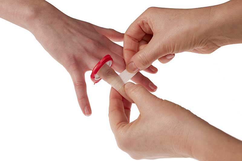 Bandaged finger with condom from Finger Cut Kit displaying a finger cut repair solution