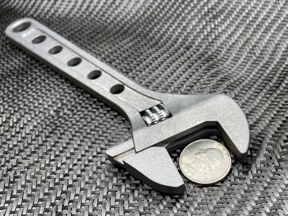 Adjustable metal wrench gripping a quarter, featuring the 8 Inch Titanium Adjustable Wrench