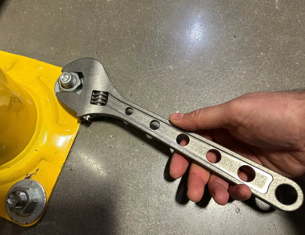 Adjustable titanium wrench held over a vibrant yellow surface showcasing corrosion resistance