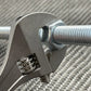 Adjustable Wrench gripping a metal bolt - Titanium 6 Inch NSN Pending product image