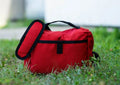 Red insulated lunch bag with black trim from Adventure Kit in Coyote Tan and Ranger Green
