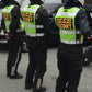 Three motorcycle escorts in high visibility vests stand in a line showcasing ANSI II Cert