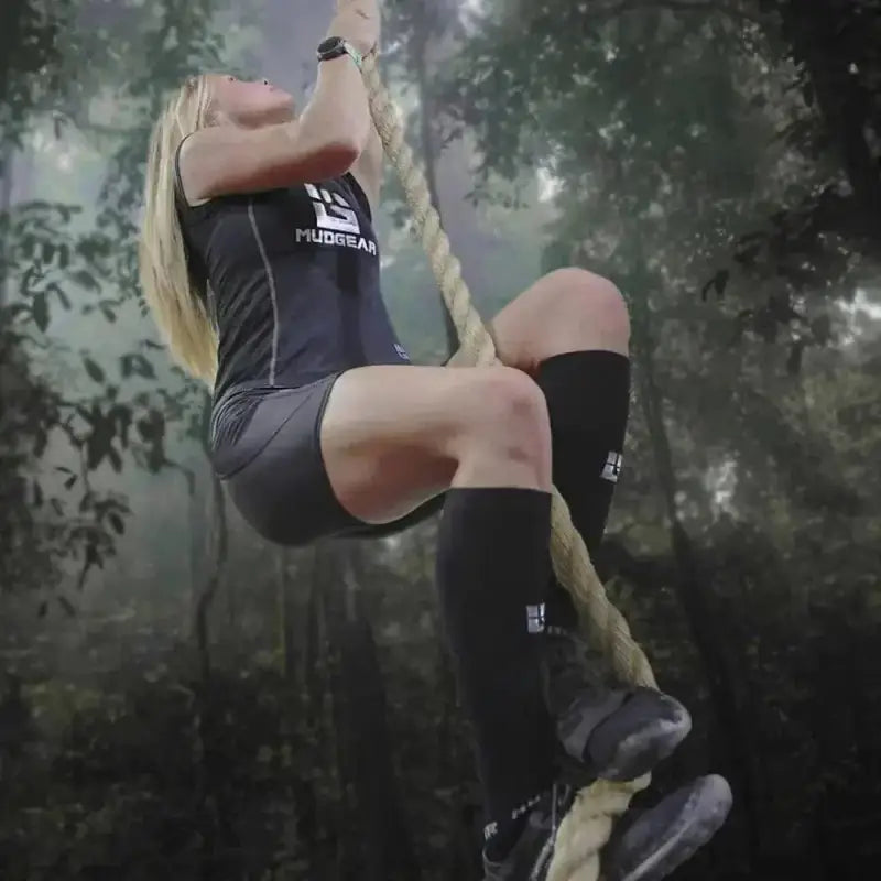 Athlete in black athletic wear climbing rope, showcasing Tall Compression Socks in Black Gray