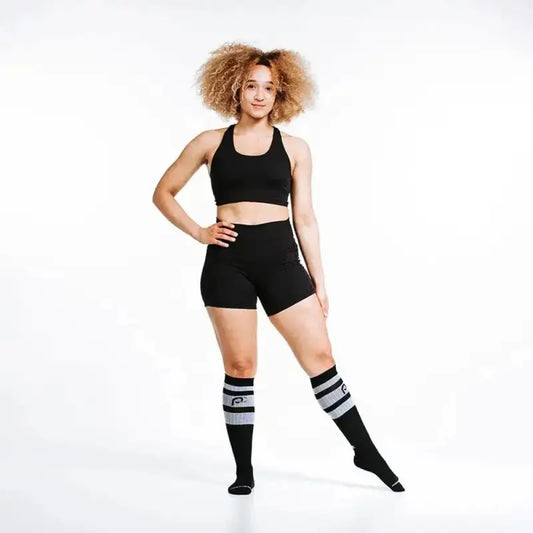 Athletic figure in black workout attire and black classic stripe knee-high socks