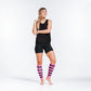 Athletic figure in black workout attire showcasing neon pink calf compression sleeves