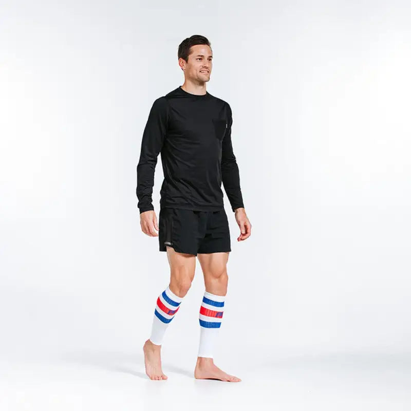 Athletic figure in black workout clothes with red-white-blue striped compression calf sleeves