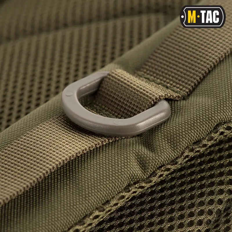 D-ring attachment point on olive green tactical webbing of M-Tac Assault Pack