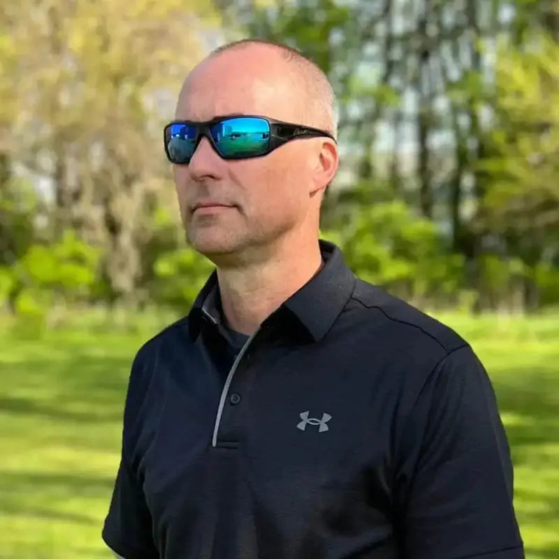 Person in black Under Armour polo wearing METEL M30 Safety glasses with blue mirror lens