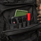 Black M-Tac Assault Pack with organized pockets, notebook, and tools in large zippered compartments