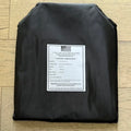 Black ballistic plate with white label showing model threat level and size for body armor