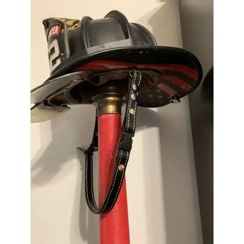 Black firefighter helmet on a red pole with smooth leather chin straps attached