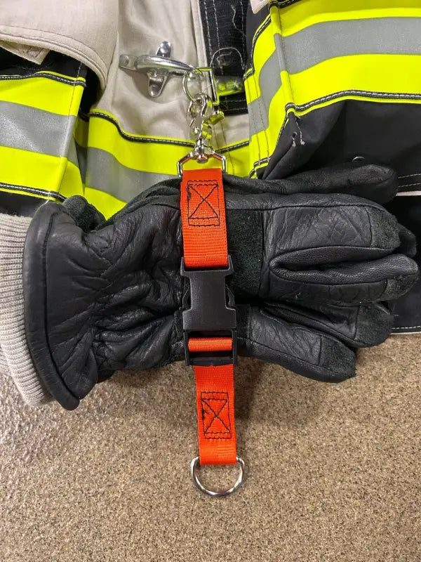 Black firefighting gloves on an orange glove strap for first responders safety