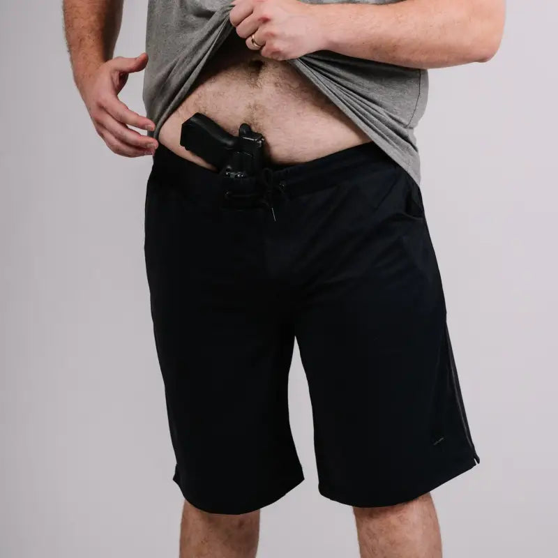 Black handgun holstered in Carrier Shorts - Midnight Black 11 with patented carrier retention