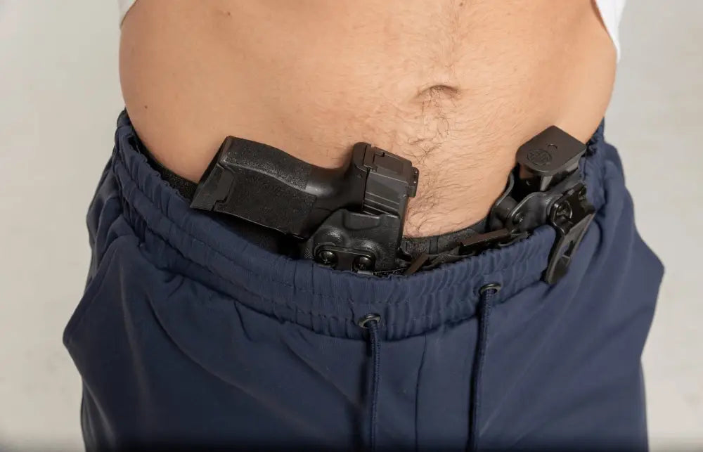 Black handgun in waistband of Navy Blue Carrier Shorts with patented carrier retention