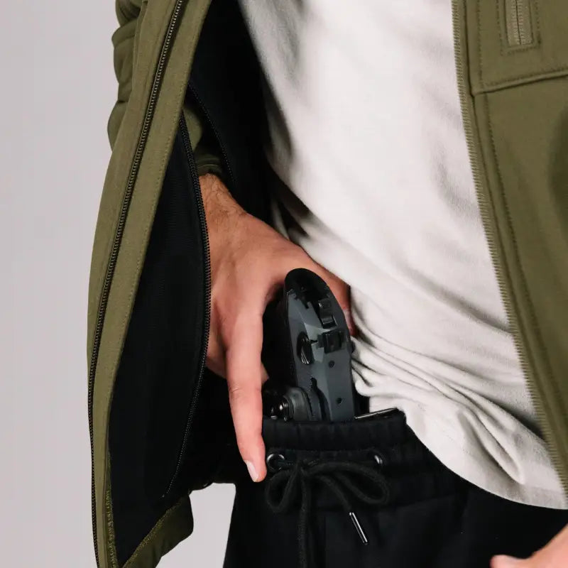 Black handgun in hand pocket of Tactical Jacket Bravo for covert concealment