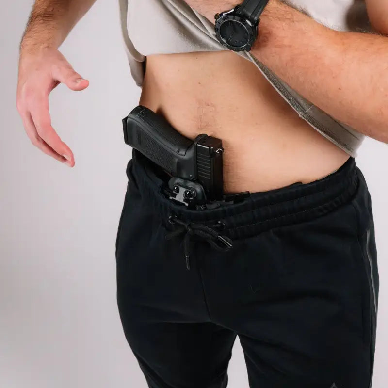 Black handgun tucked in waistband of Carrier Joggers Mk.II with patented carrier retention