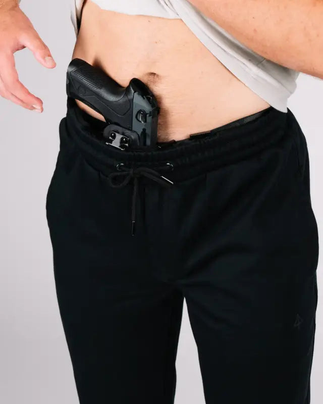 Black handgun in waistband of NEW Carrier Sweatpants Mk.II with patented carrier retention