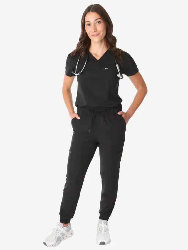 Black women’s tuckable one-pocket scrub top with jogger-style pants and stethoscope