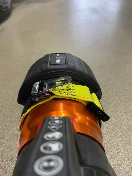 Black and orange ski boot with dials showcasing the innovative extrication tool carrying strap