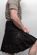 Black pleated utility kilt with cargo pockets displayed on a model wearing Standard Blackout Utility Kilt