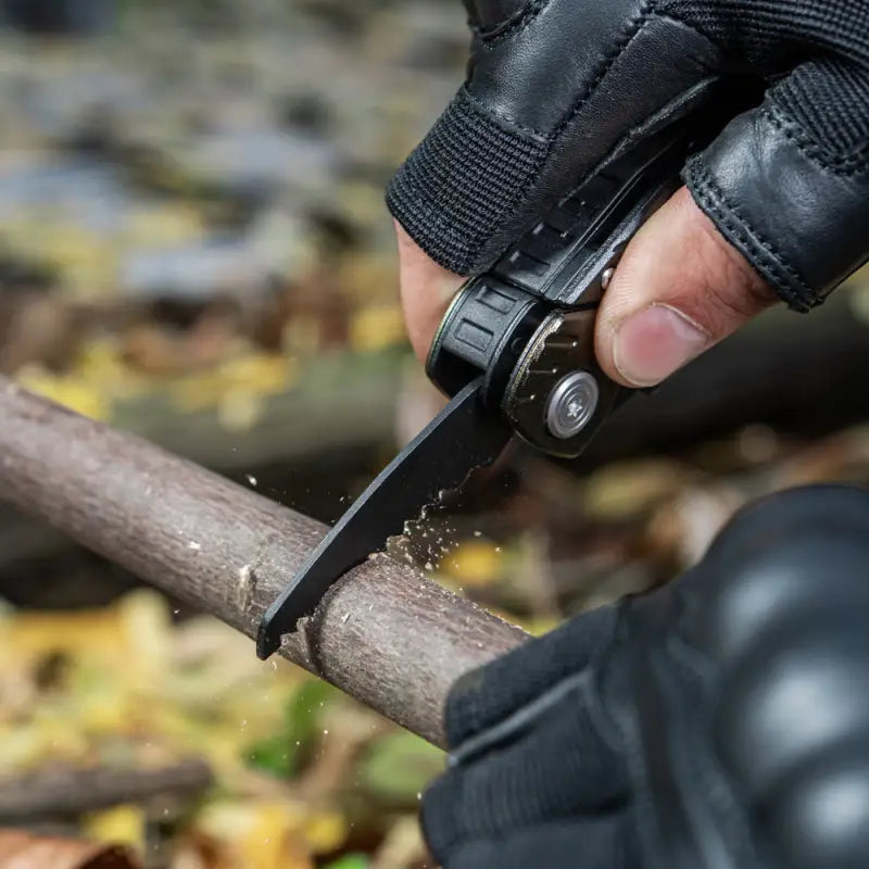 Black folding pocket knife from M-Tac Universal Tool Type 2 cutting a wooden branch