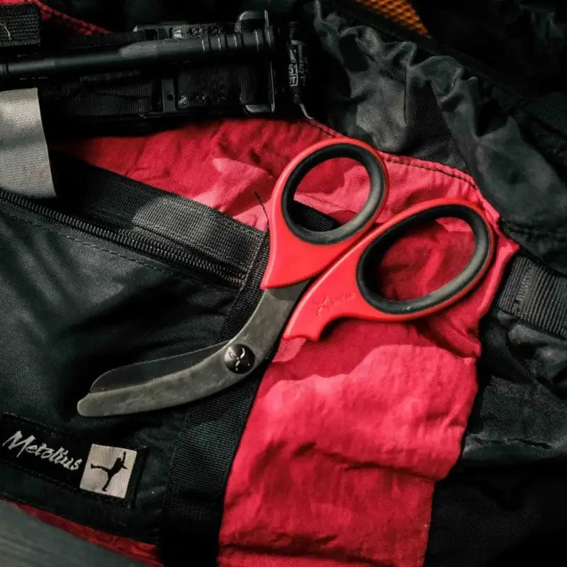 Black titanium coated trauma shears on red fabric with a black bag for emergency professionals