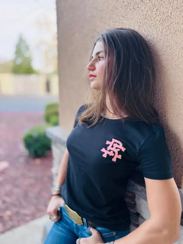 Black Woman’s Staple Tee featuring a stylish pink logo design on the chest