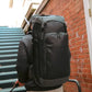 Black tactical backpack with compartments and adjustable tie-down for discreet rifle storage