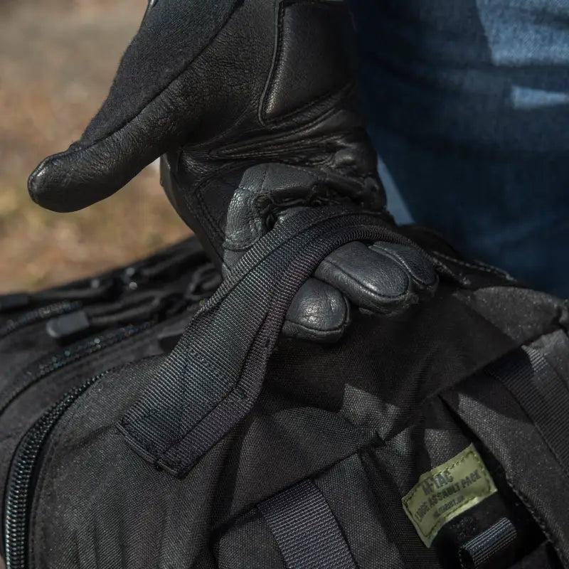 Black M-Tac Assault Pack featuring straps, webbing, and large main zippered compartments