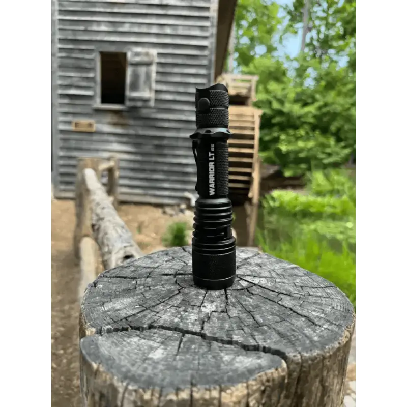 Black Warrior LT-G5 Long Throw Tactical Flashlight on a weathered tree stump