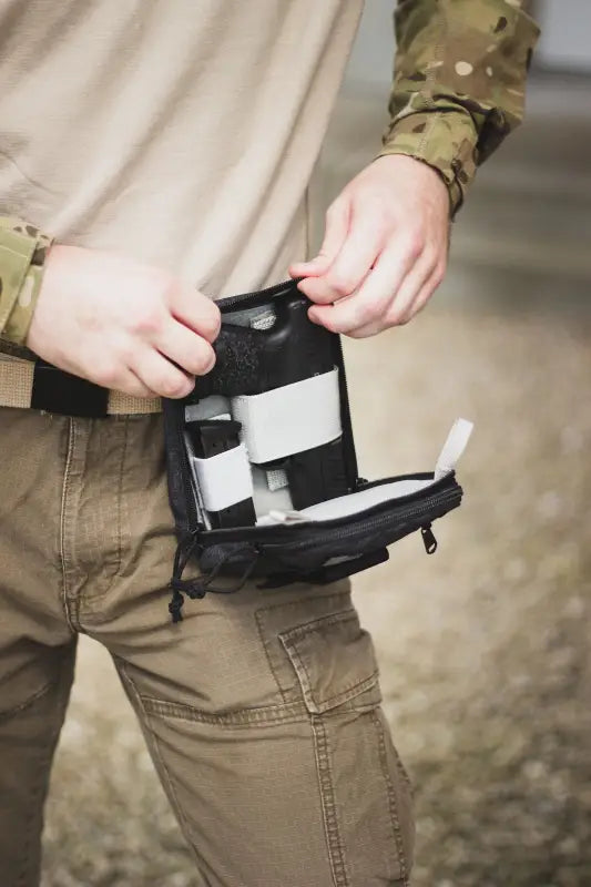 Black tactical medical pouch being opened from the Liberty Gun Pack for easy access