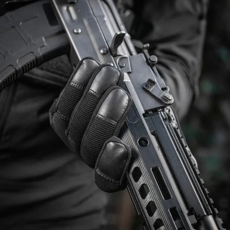 Black tactical rifle held by a gloved hand wearing M-Tac Gloves Police Gen.2