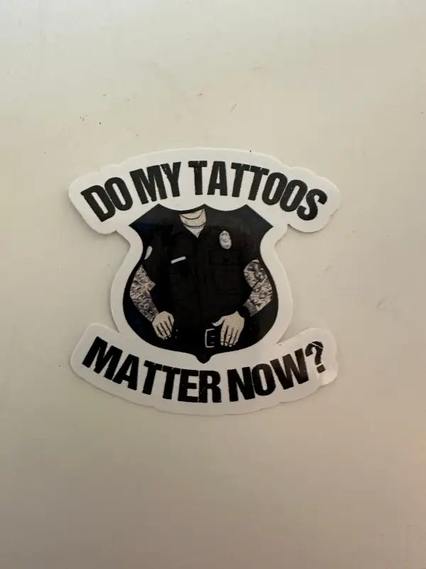 Black and white sticker of a tattooed police uniform asking if tattoos matter now