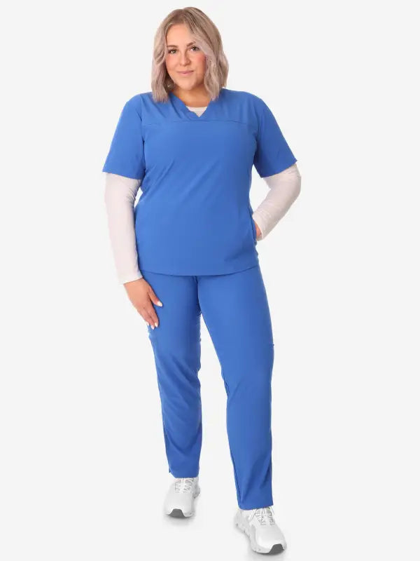 Blue medical scrubs with a women’s long-sleeve underscrub and stylish sneakers